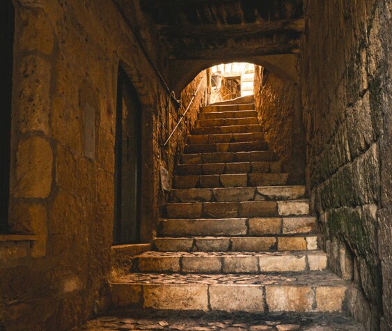 Escalier ancien exterieur avec un passage étroit et une voute ancienne basse