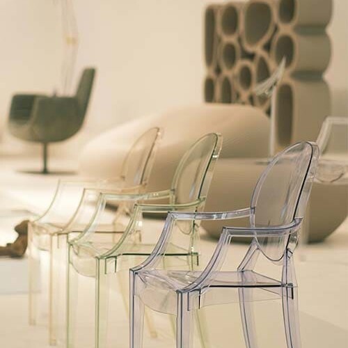 Chaises design aligné dans un showroom avec des fauteuils de créateur en second plan