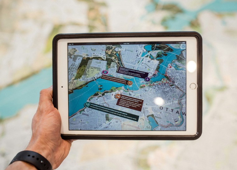 Une main tient une tablette qui affiche la localisation de 4 &eacute;quipes